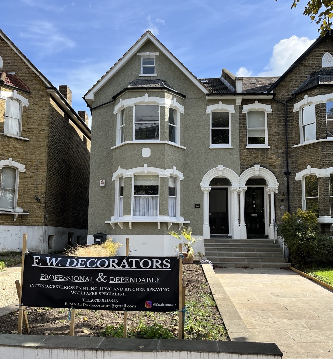 Completed grey exterior with white window detailing and an F.W.Decorators banner in the front garden