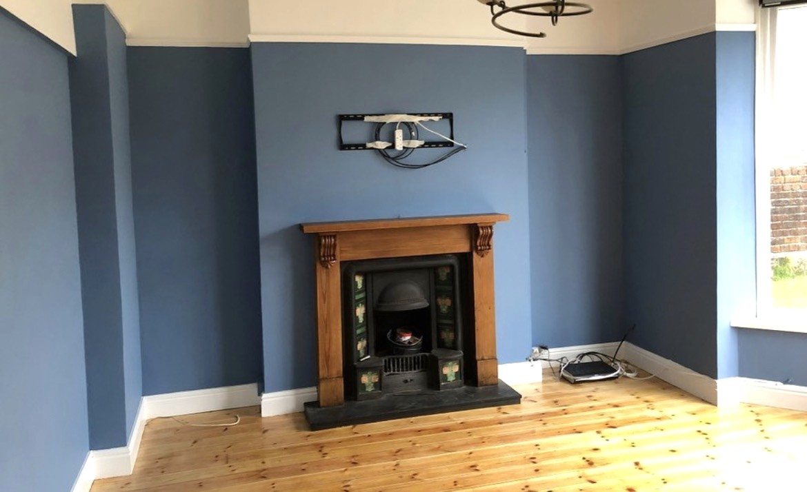 Blue painted living room with white detailing, timber mantel and restored pine floor